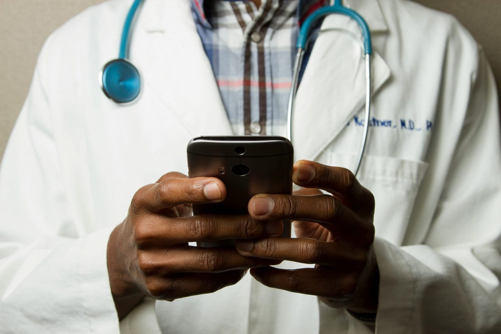 Artificial Intelligence in Healthcare: How AI is Changing the Industry 3 person wearing lavatory gown with green stethoscope on neck using phone while standing